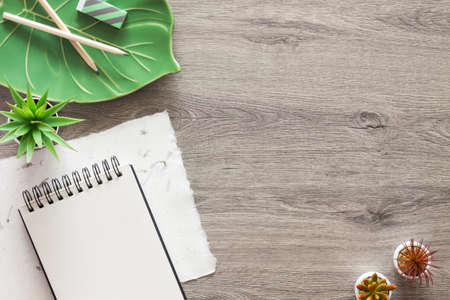 Creative wooden desk with an open sketchbook and ceramic monstera leaf. Copy space.の写真素材