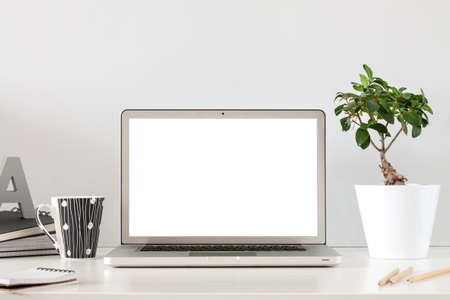 A business desk against a gray wall with an open laptop. Mockup screen.の写真素材
