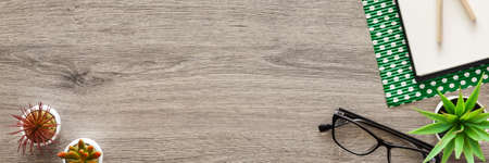 Wooden home desk with an open sketchbook. Copy space. Green dotted paper. Panorama.の写真素材