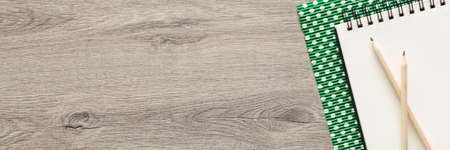 Wooden home desk with an open sketchbook. Copy space. Green dotted paper. Wooden pencils. Panoramicの写真素材
