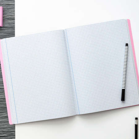 Blank notebook is open on modern white working table. Top view. Mockup with pastel pink elements. Black and white geometrical concept.の写真素材