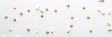 Scattered pills on a white background. Bright monochrome composition. Pharmacology. Panoramic photoの写真素材
