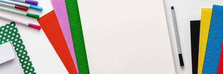 Creative school desk with sketchbook mockup. Colorful school supplies. Papers and markers. Place for text. Panoramic view from above. Real photoの写真素材