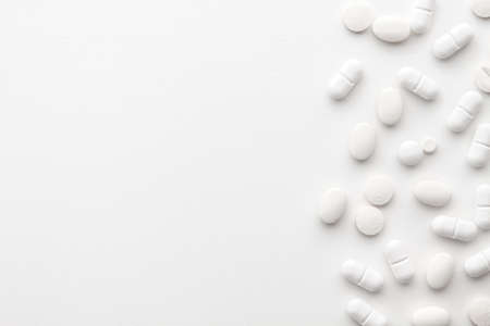 Scattered white pills on a white background. Bright monochrome composition. Pharmacology. Copy spaceの写真素材