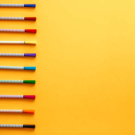 A blank yellow background with room for your text. Copy space. Colorful markers arranged in a row. Concept desk. Back to school. View from aboveの写真素材