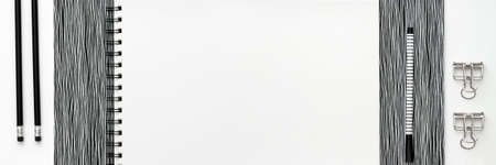 Open notebook, sketchbook or scrapbook with white blank page on the white table. Ideas, notes, plan writing or sketching concept. Panoramic top view mockup.の写真素材