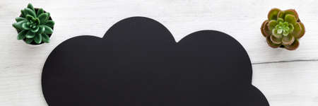 Black cloud with space for text on white wooden table. Copy space. Top view. Green succulents....