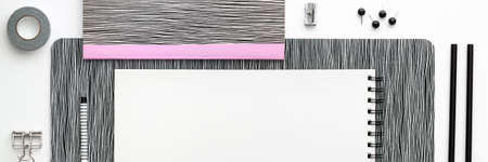 Open notebook, sketchbook or scrapbook with white blank page on the white table. Black and white concept. Panoramic top view mockup. Pastel pink office toolsの写真素材