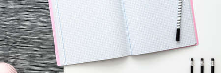 Blank notebook is open on modern white working table. Top view. Mockup with pastel pink elements. Panoramic black and white concept.の写真素材