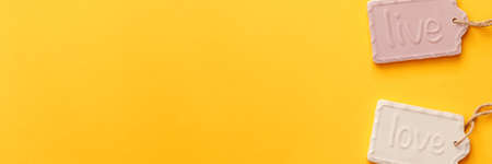 A blank yellow background with space for text. Copy space. Ceramic decorations with the letters live and love. Pastel colors. Concept composition. Panoramic real photoの写真素材