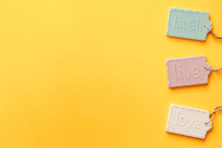 A blank yellow background with space for text. Copy space. Ceramic decorations with the letters laugh, live and love. Pastel colors. Concept compositionの写真素材