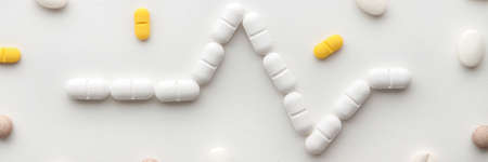 Scattered colorful pills on a white background. Pharmacology. Heartbeat, cardiogram. Panoramic photoの写真素材