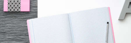 Blank notebook is open on modern white working table. Panoramic top view real photo. Mockup with pastel pink elements. Black and white concept.の写真素材