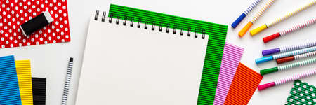 Creative school desk with sketchbook mockup. Colorful school supplies like papers and markers. Place for text. Panoramic top viewの写真素材