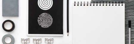 Flat lay skretch book mockup with black office supplies on white background. Top view mockup. Panoramic blog template. Black and white geometrical concept.の写真素材