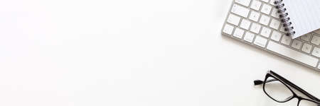 White desk with copy space. Computer keyboard and office supplies. View from above. Panorama.の写真素材