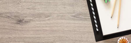 Wooden home desk. Copy space. Open sketchbook and office supplies. Plants. View from above. Panorama.の写真素材