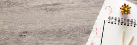 Wooden home desk. Copy space. Drawing supplies, handmade paper, open sketchbook and succulents. View from above. Panoramic photo.の写真素材