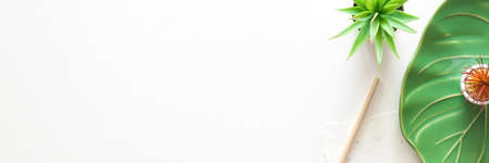 A creative desk at home. Copy space. View from above. Ceramic monstera leaf. Panoramaの写真素材