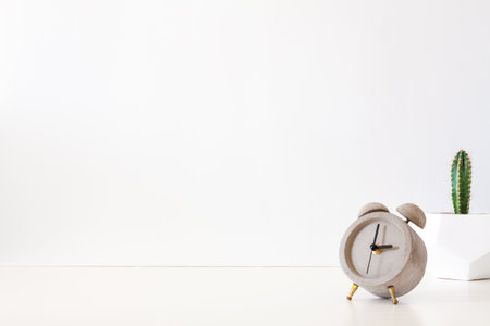 A desk against a white wall. Copy space. Cactus in a geometric pot. Concrete clock.の写真素材
