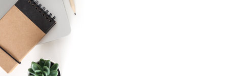 White desk in the office. View from above. Notebook and plant. Copy space. Panoramaの写真素材