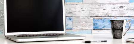Home office. Open laptop with blank screen. A wall made of old boards. Mockup. Copy space. Banner.の写真素材