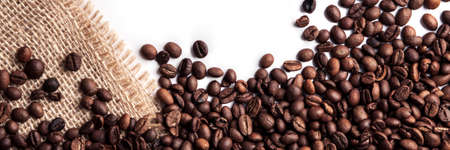 Panoramic background of roasted coffee beans on a white background with a jute sackの写真素材