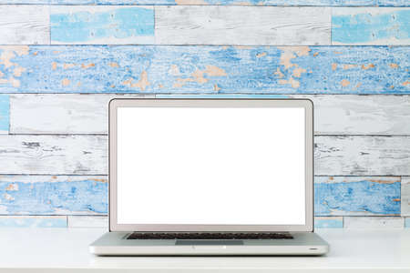 An open laptop on a white desk. Mockup. A wall made of old blue boards.の写真素材