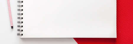 White school creative desk with red elements. Space for text. Copy space sketchbooks. Panoramic top view. School accessories. Simple compositionの写真素材