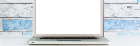 An open laptop on a white desk. Mockup. A wall made of old blue boards. Bannerの写真素材