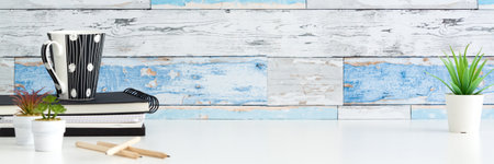 Succulent plant in a white pot and a cup with coffee and office supplies. A wall made of old blue boards. Copy space. Bannerの写真素材