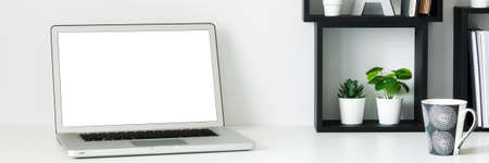 Home office. A desk against a white wall. Copy space. Open laptop. Mockup. Geometric composition....