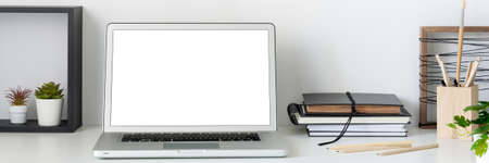 Home office. Desk with an open laptop against a white wall. Mockup. Copy space. Books on the desk. Bannerの写真素材