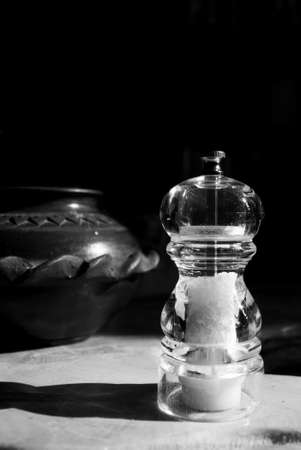Classy transparent salt grinder with a clay pot in the background shot in black and whiteの写真素材