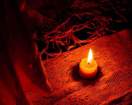 A Single bee wax candle on a orange scarf. Low keyの写真素材