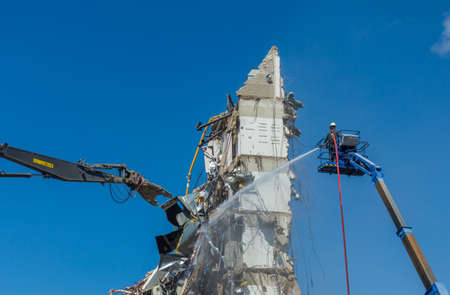 Industrial worker wetting the surface of a building during demolitionの写真素材