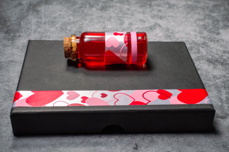 Close-up image of a love potion in a glass  bottle on top of a gray paper gift box
