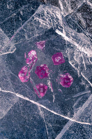 Image of a set of rpg dice beneath a sheet of ice in the winter's sunの写真素材