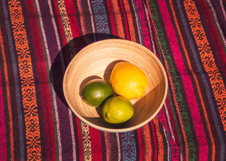 Bamboo bowl with two limes and a lemon on a colorful fabricの写真素材