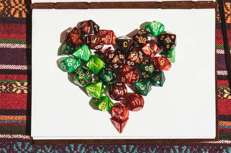 Overhead image of a heart symbol created with green and red Role-playing gaming dice on top of an...
