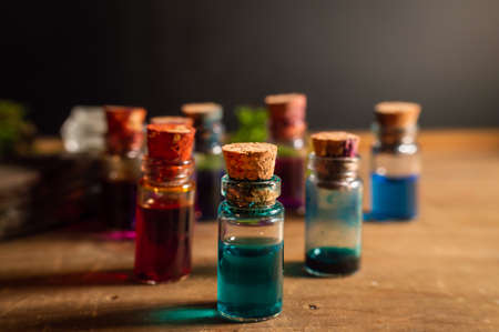 Close-up image of a small glass stopper bottle filled with blue liquid. Within the background other small bottles filled with various colored liquid.の写真素材