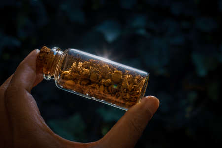close-up image of someone holding a glass stopper bottle filled with dried chamomileの写真素材