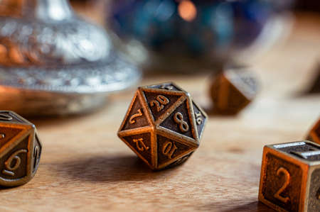 Close-up image of a metal 20-sided role-playing gaming die on a wooden surfaceの写真素材