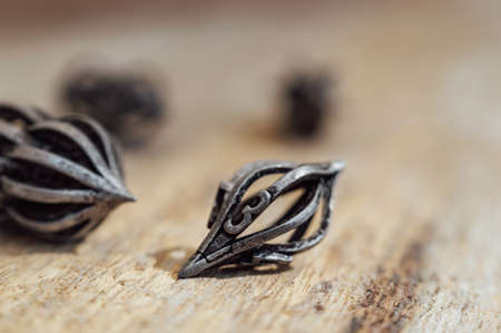 Droplet-shaped metal RPG dice on a wooden surface in the sunの写真素材