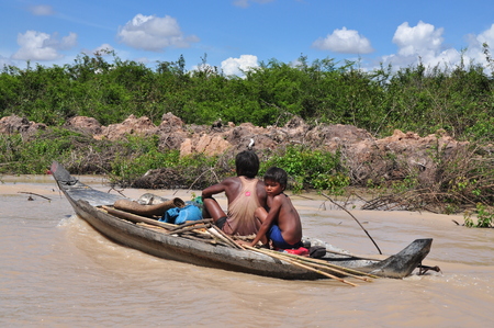 Near Kampong Phluk, Cambodia- August 24, 2012: Cambodian father and son on small boat.のeditorial素材