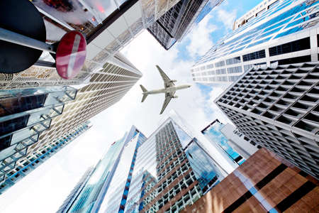 Airplane flying over business skyscrapersの写真素材