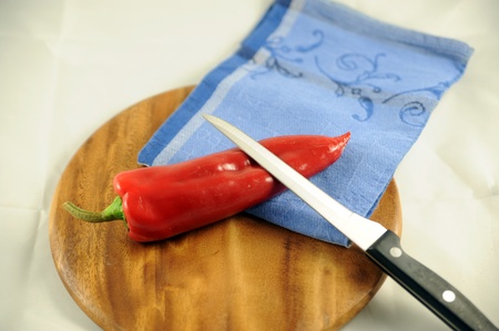 Peperoni on a board with knife and tableclothの写真素材