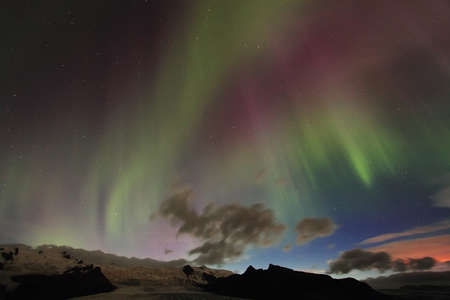 Aurora borealis or the northern lights and red bardarbunga eruption glowing in Icelandの写真素材