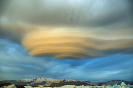 Jokulsarlon Glacial Lagoon of Vatnajokull glacier under majestic lenticular clouds, Icelandの写真素材