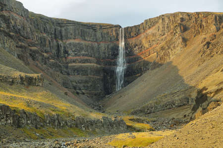 Hengifoss waterfall in Iceland. This waterfall is surrounded by basaltic strata layers and red layers of clay.の写真素材